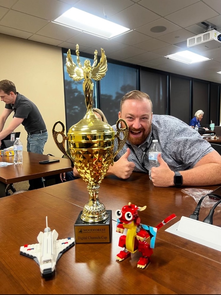 Daniel giving a thumbs up behind the Digital Channels Cup trophy